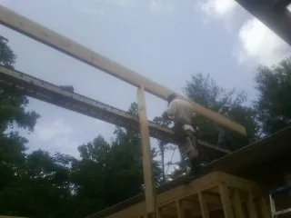 Carpenter setting a ridge beam over a new addition frame — Ice Dam Removal by Roofing Brothers in Manistee