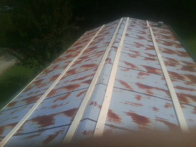 Rusted metal roof panels with new wood purlins before replacement — Storm Damage Roof Repair in Manistee by Roofing Brothers