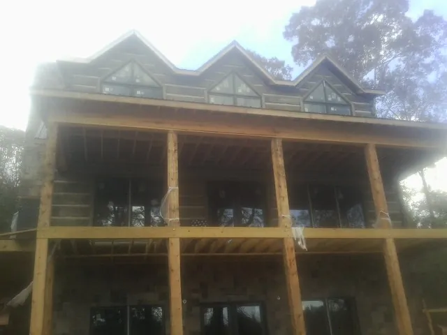 Dormers and porch framing on a large log home under construction — Roof Coating work by our crew in Manistee