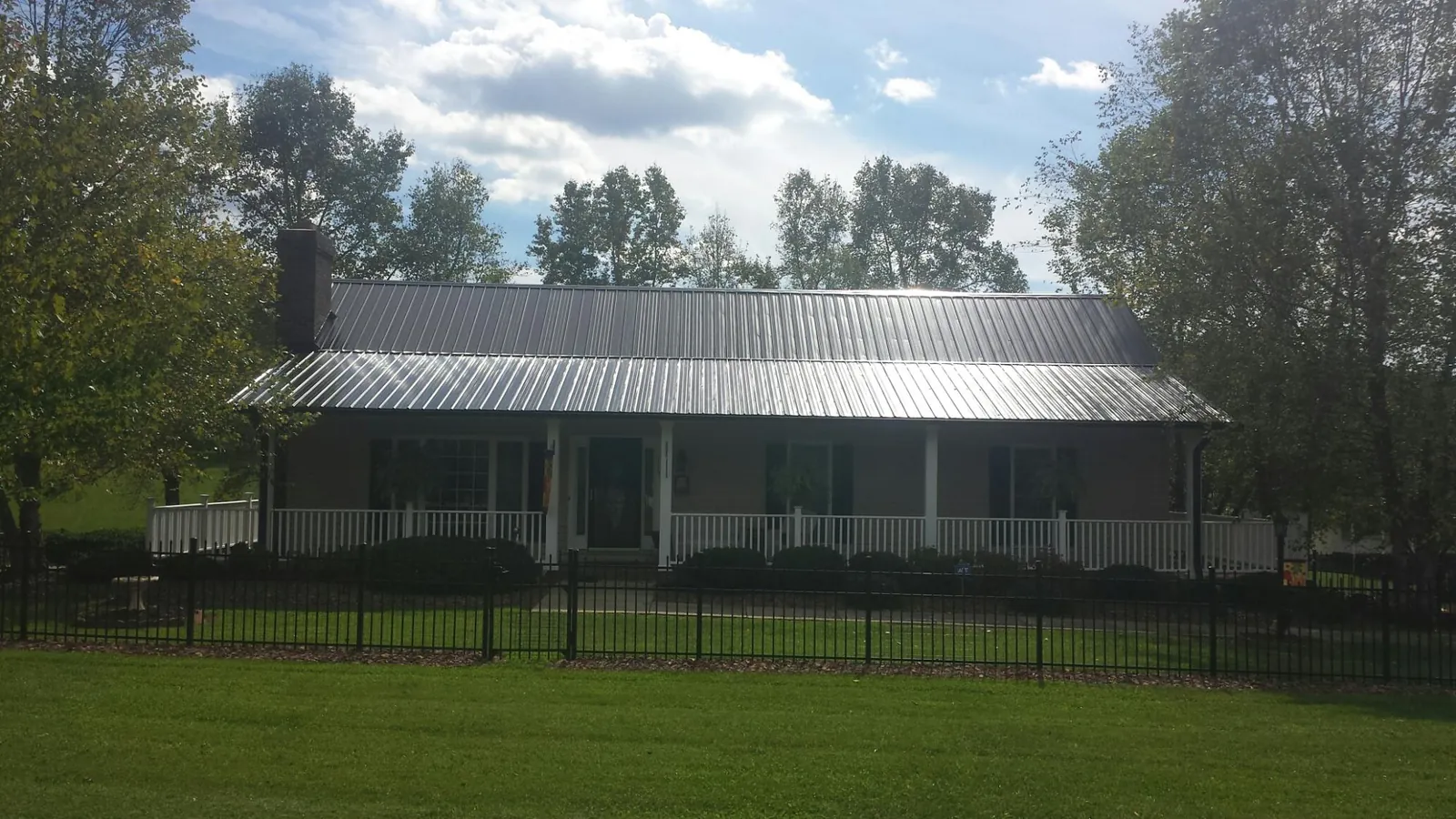 Gray metal roof on a brick ranch with a full width front porch — Gutter Guard Installation work by our crew in Manistee