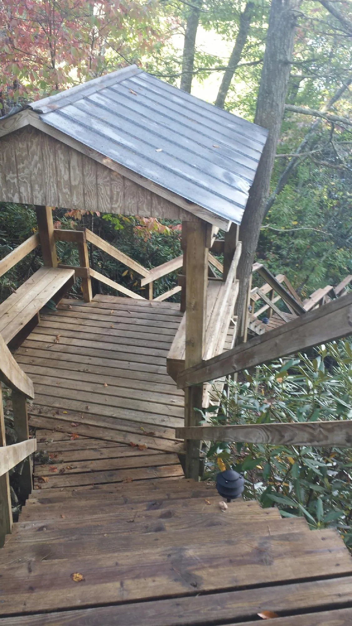 Metal roofed shelter over wooden steps on a wooded walkway — Skylight Repair & Installation work by our crew in Manistee
