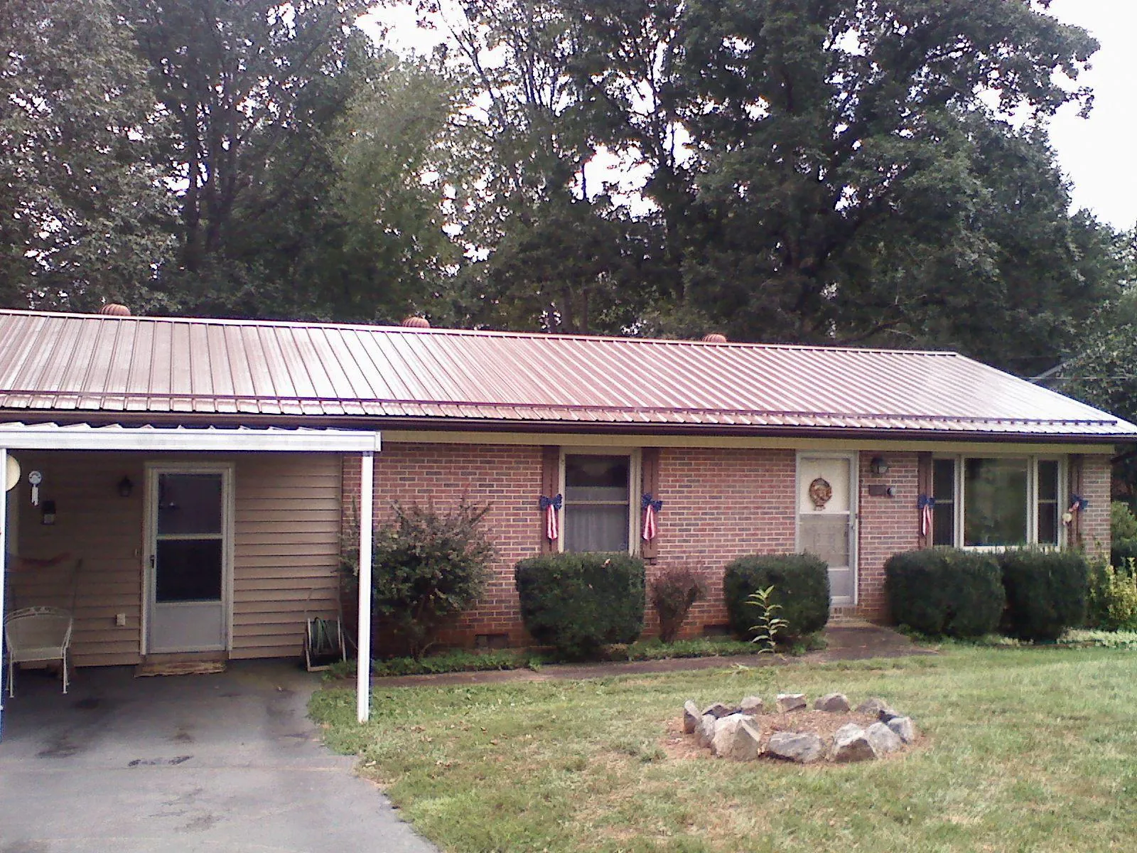 Bronze metal roof and carport on a brick ranch home — Roof Repair work by our crew in Manistee