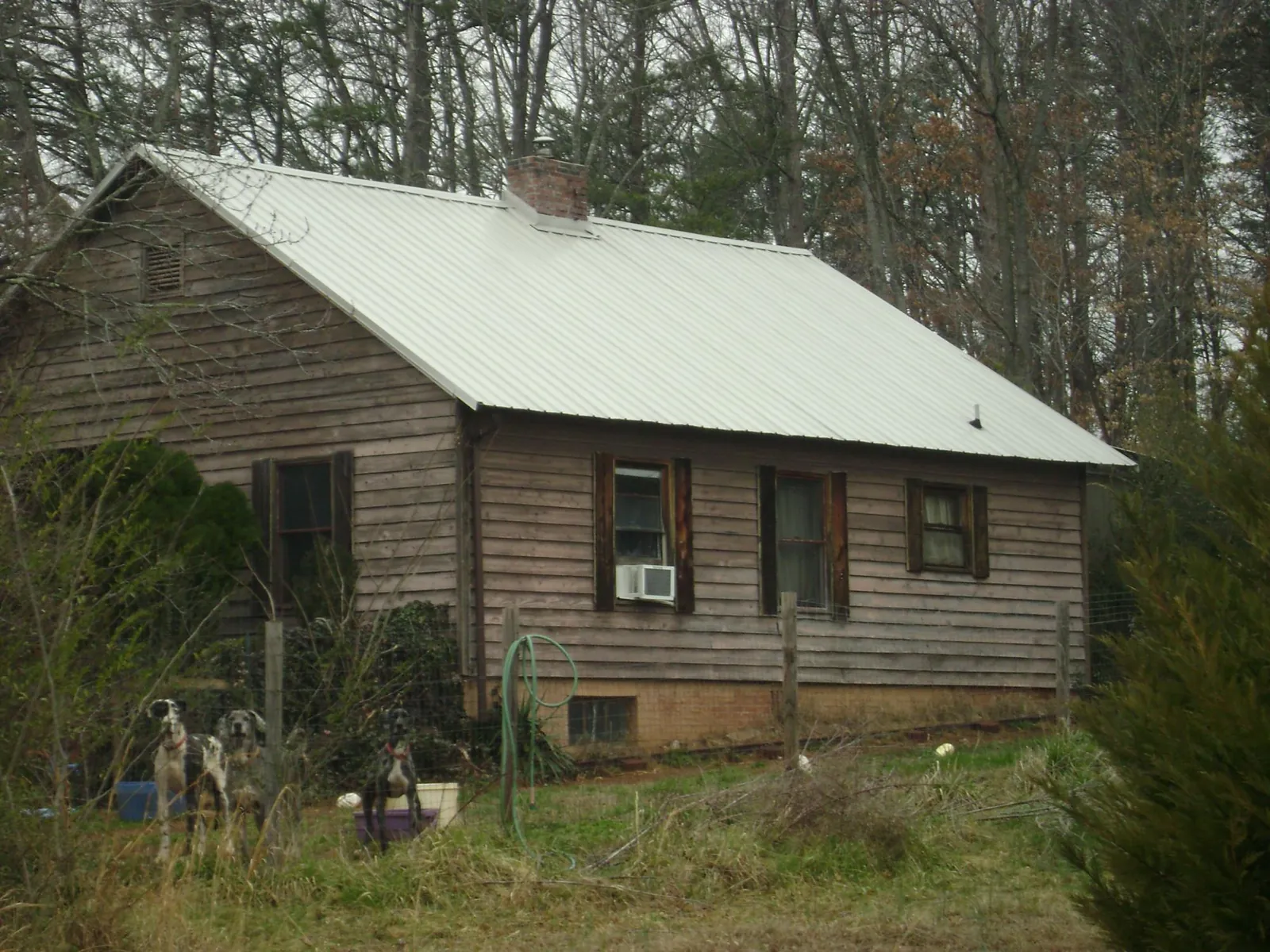 White metal roof on an old wood sided farmhouse, from a Metal Roof Installation job in Manistee